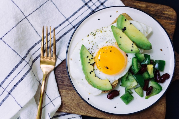 Een gezond ontbijt van toast met avocado, volkoren brood en gebakken ei en burrito salade op een witte plaat. Bovenaanzicht