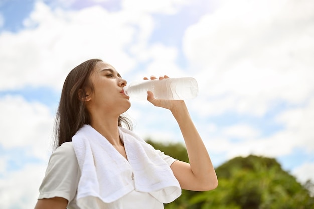 Een gezonde Aziatische vrouw drinkt water uit een fles die na een lange duurloop dorstig rust