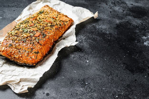 Een gezonde, eiwitrijke, gerookte Atlantische zalmfilet. forel. Zwarte achtergrond, bovenaanzicht, ruimte voor tekst