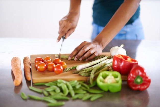Een gezonde en gezonde maaltijd bereiden Bijgesneden close-up shot van een vrouw die groenten snijdt op een snijplank