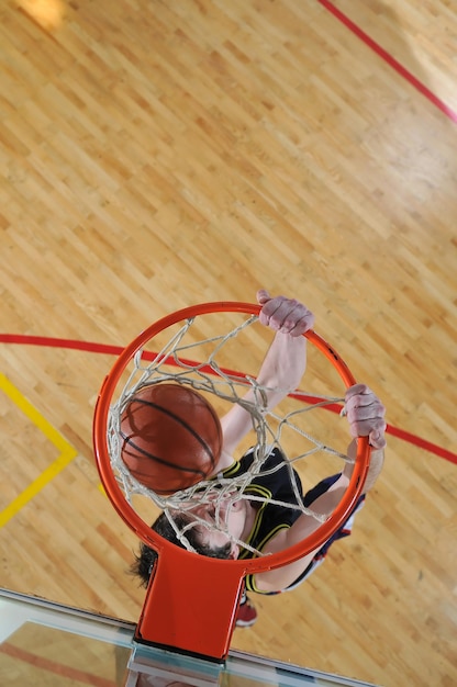 Een gezonde jonge man speelt basketbal in de school.