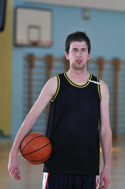 een gezonde jonge man speelt basketbalspel in de gymzaal van de school binnen