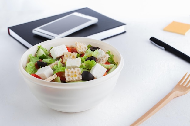 Een gezonde lunch op kantoor Lunchbox met groentesalade op tafel bij de computer