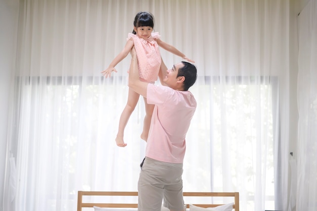 Een gezonde vader houdt gelukkige schattige dochter vliegen en vliegtuig spelen samen thuis in het weekend, familie concept.