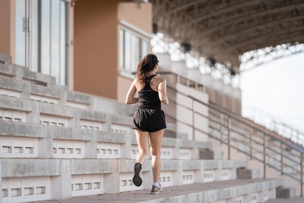 Een gezonde volwassen Aziatische vrouw rent op betonnen trappen van het stadsstadion om het lichaam te versterken