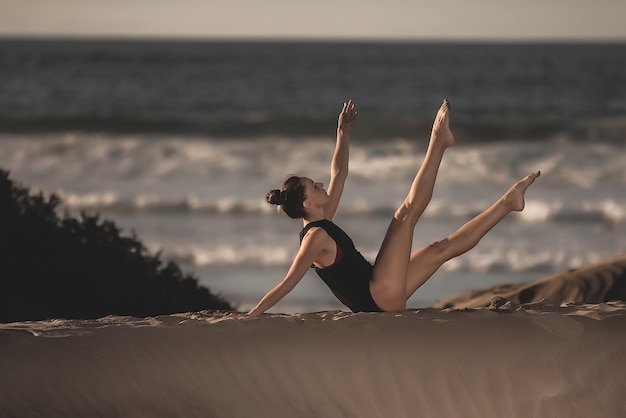 Een gezonde vrouw die yoga beoefent aan de kust.