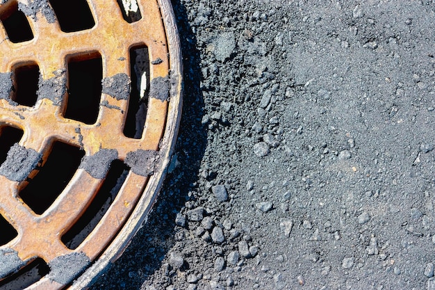 Een gietijzeren stormriool komt op de weg voordat de asfaltverharding wordt gelegd die is gegoten met bitumen Afvoer van regenwater van het wegdek Close-up