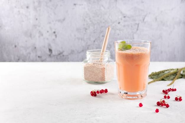 Een glaasje smoothies gemaakt van rode bessen en kokosmelk met de schil van weegbree zaden