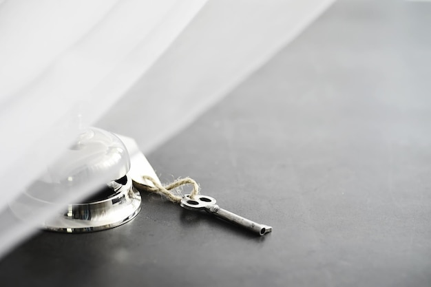 Foto een glanzend zilveren metalen bel bij de receptie van het hotel. een tafel in het hotel bij de conciërge met een bel en een deursleutel. sleutel en bel in een hotel.