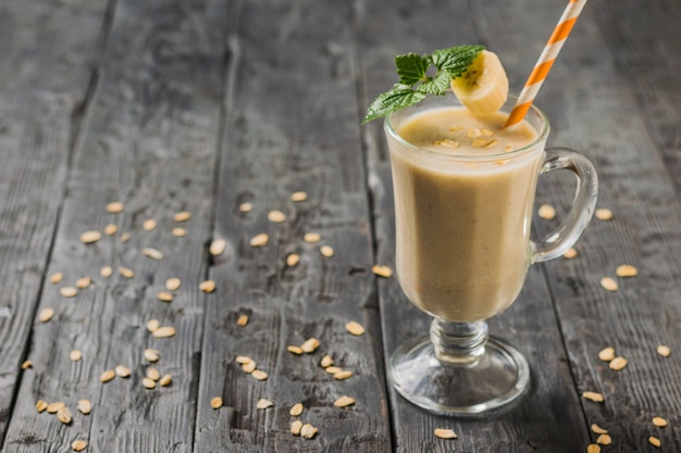 Een glas banaan smoothie en munt op een houten tafel