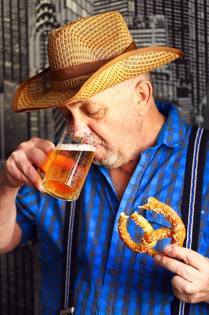 Een glas bier en een krakeling in de handen van een man.