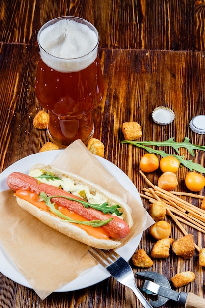 Een glas bier en snacks op een houten tafel.