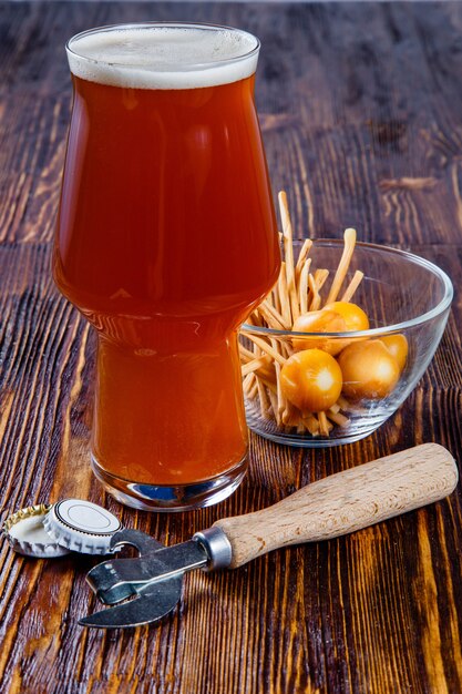 Een glas bier en snacks op een houten tafel.