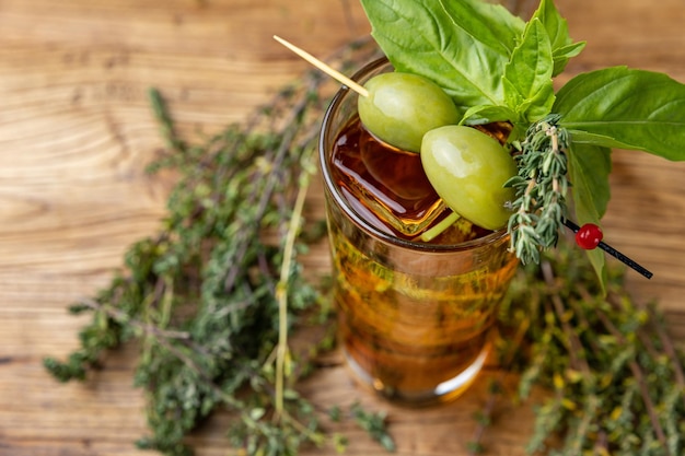 Een glas cocktail met een groene olijf erop en een bosje rozemarijn erop.