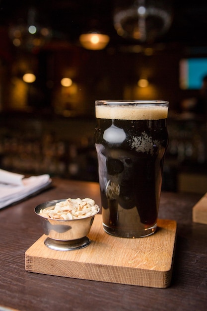 Een glas donker bier met noten op de verticale foto van de bar