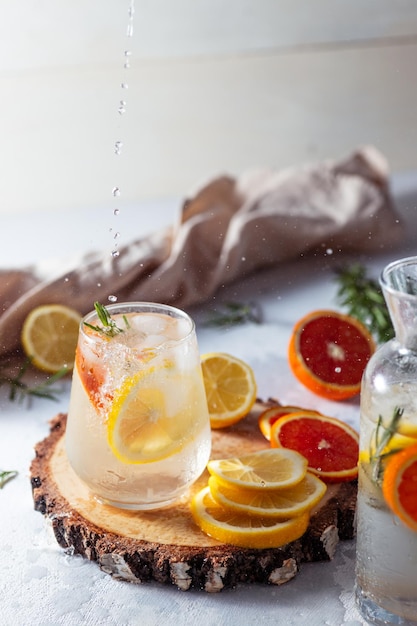 Een glas en een karaf limonade Citroen- en grapefruitschijfjes met rozemarijnblaadjes in een drankje