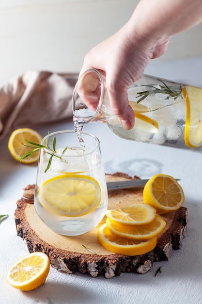 Een glas en een karaf limonade Citroenschijfjes met rozemarijnblaadjes in een drankje