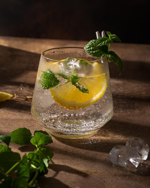 Een glas frisdrank, citroenmunt en ijs staat op een bruine houten tafel