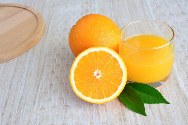 Een glas jus d'orange naast sinaasappelen en groene bladeren geïsoleerd op pastel achtergrond