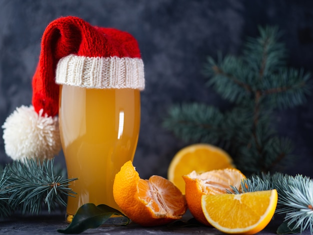 Een glas kerstbier in een kerstmuts op een donkere tafel