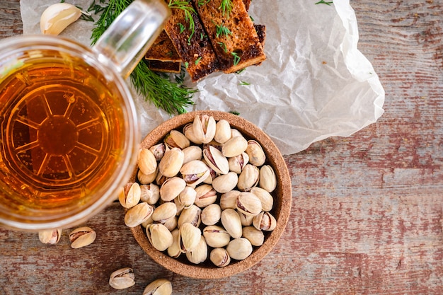 Een glas light bier, knoflook rogge toast met een dille en pistachenoten op een houten tafel.