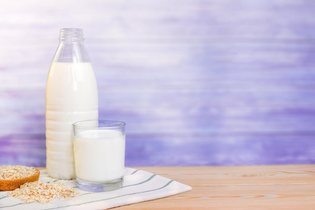 een glas melk en een plastic fles met melk op een houten tafel