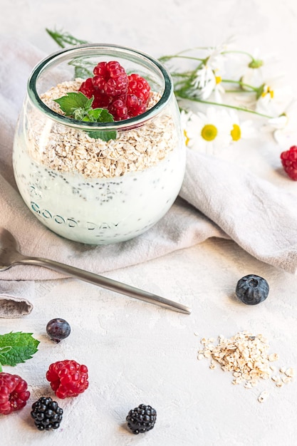 Een glas met gelaagde yoghurt chiazaden, haver en bessen geserveerd als ontbijt