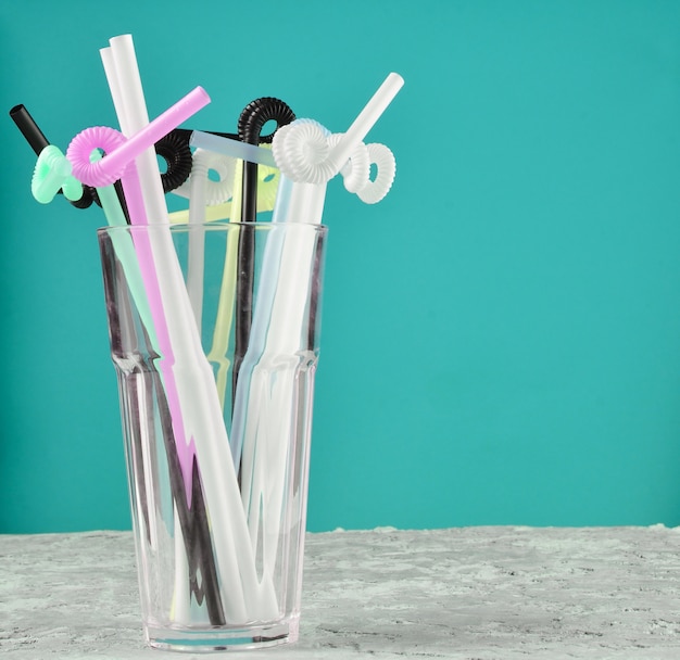 Foto een glas met veel gekleurde cocktailbuizen op een groene achtergrond