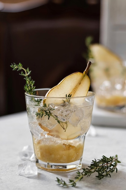 Een glas perencocktail met een schijfje rozemarijn op de rand.