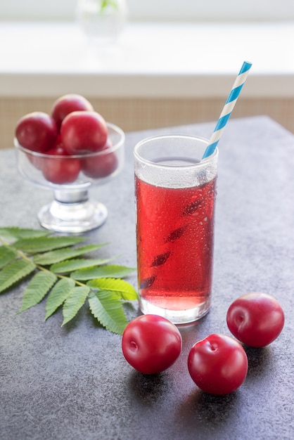 Een glas pruimendrank, transparant rood en pruimenfruit op tafel