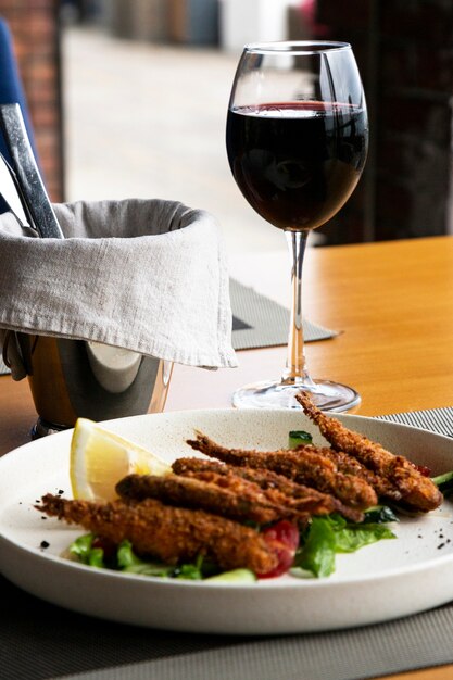 Een glas rode wijn en zeevruchten: vis met groenten en gebakken mosselen in het restaurant