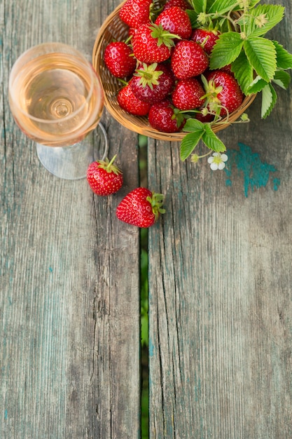 Een glas rose wijn geserveerd met verse aardbeien op houten achtergrond