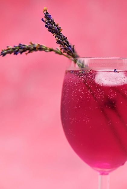 Een glas roze cocktail op een magenta achtergrond met kleurovergang