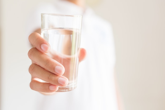 Een glas schoon mineraalwater in de handen van de mens. Concept van gezonde drank.