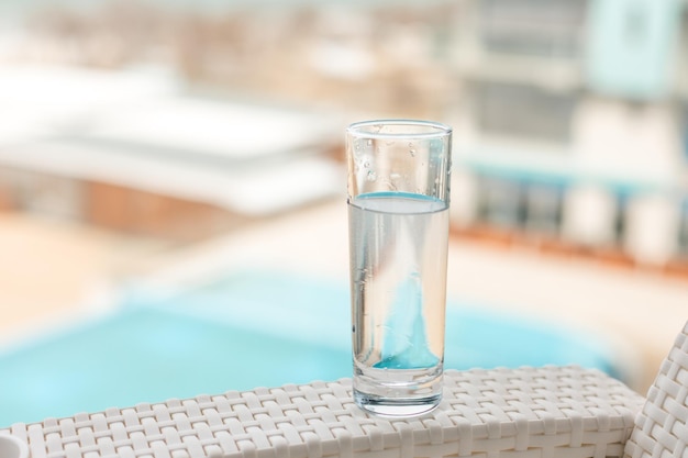 Een glas schoon water in de open lucht Glas glas met water op de achtergrond van het zwembad Soft focus
