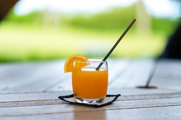 Een glas sinaasappelsap met stro op houten tafel