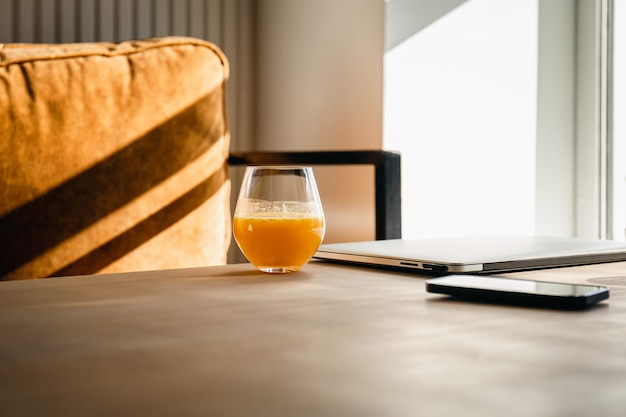 Een glas sinaasappelsap op het bureaublad in de buurt van de laptop in de ochtend