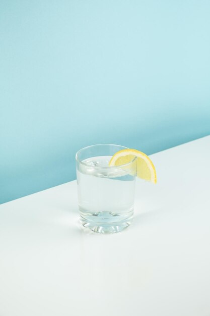 Een glas tonic op tafel tegen een witte en blauwe achtergrond