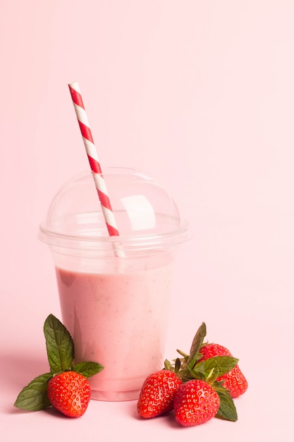 Een glas verse aardbeimilkshake op roze achtergrond