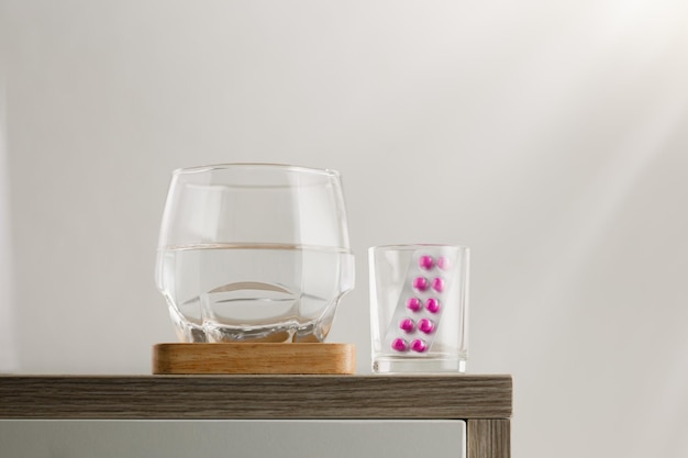 Een glas water en medicijnen op de houten tafel