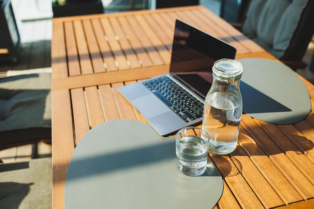 Een glas water op de achtergrond van een laptop op een zomerterras Werk in een café Op afstand werken online