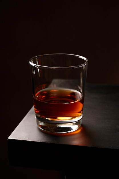 Een glas whisky met ijs op een houten tafel Low key