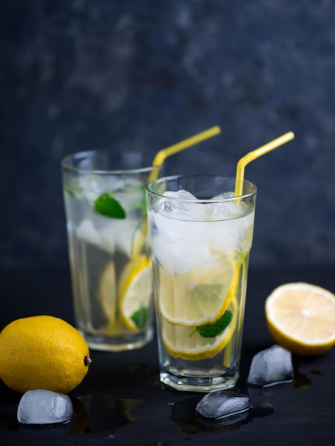 Een glas zomerlimonade met citroenmuntijs op een donkere betonnen tafel