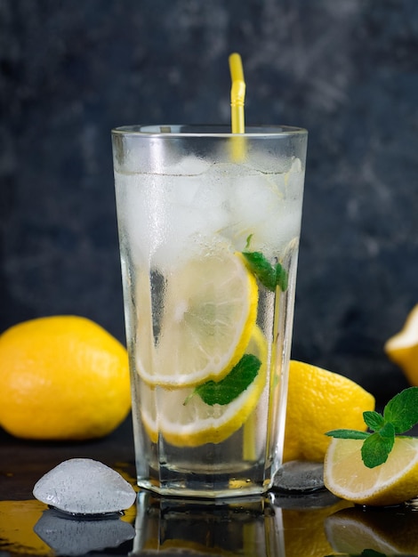 Een glas zomerlimonade met citroenmuntijs op een donkere betonnen tafel