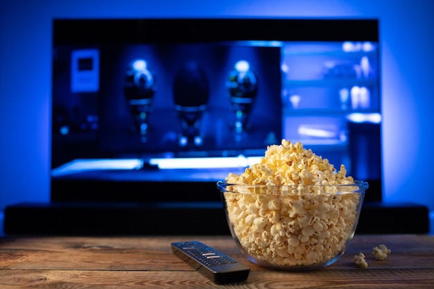 Een glazen kom popcorn en afstandsbediening op de achtergrond de tv werkt 's Avonds gezellig thuis een film of tv-serie kijken