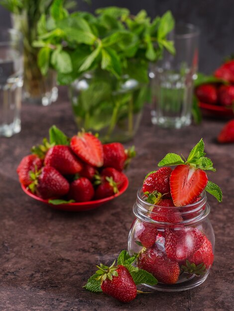 Een glazen pot rode sappige aardbeien op donkerbruine tafel