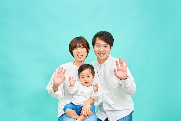 Een glimlachend gezin zwaait met hun handen voor een blauwe achtergrond