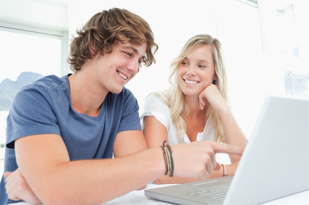 Een glimlachend paar dat laptop met de vrouw bekijkt die de man bekijkt