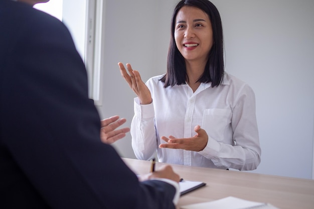 Een glimlachende aziatische vrouw beantwoordt vragen en geeft een interview voor het uitvoerend sollicitatiegesprek of werkgelegenheidsconcepten