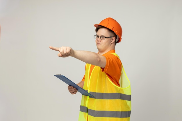 Een glimlachende jonge man met hersenverlamming in een bril in een arbeidersuniform met een kassa op zijn hoofd concept van de Werelddag van Genetische Ziekten